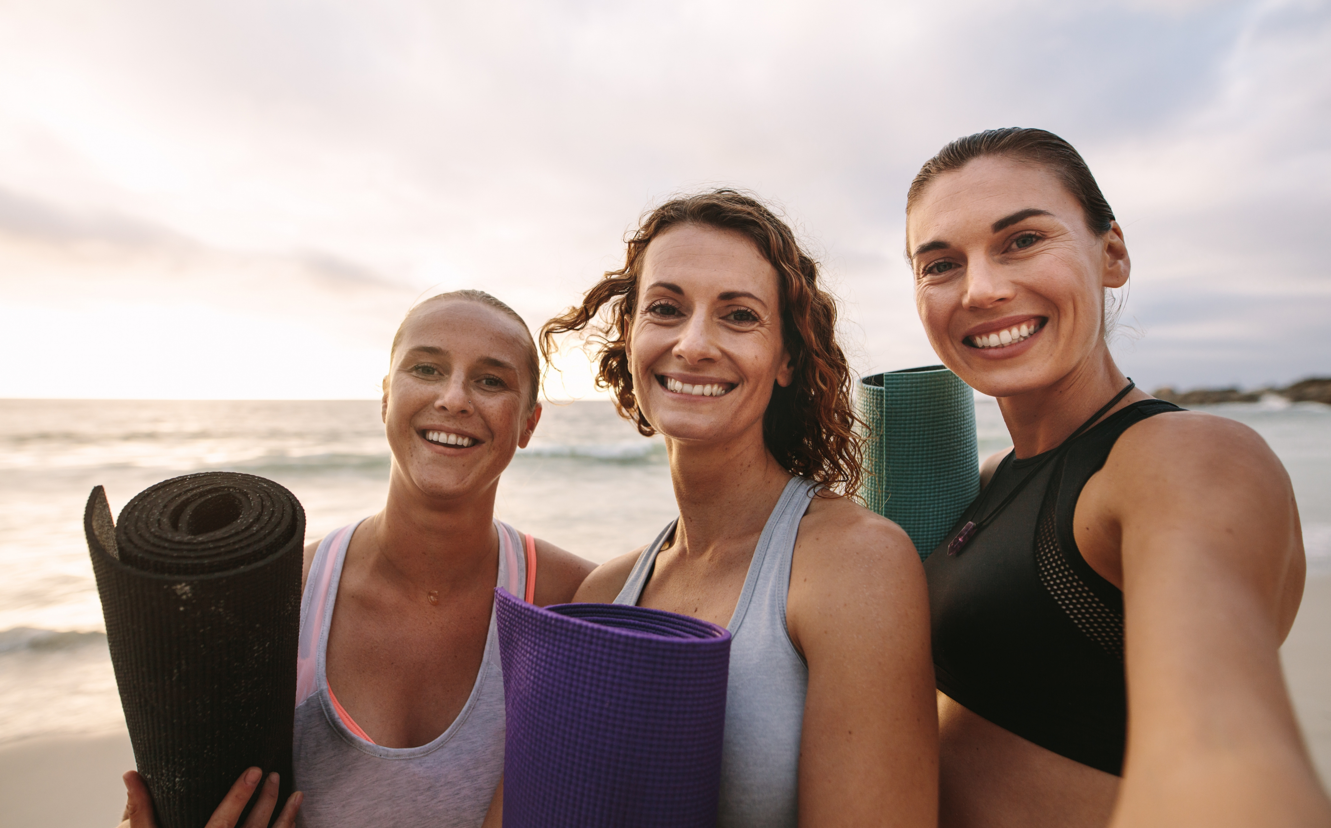3 lachende yogini's op het strand