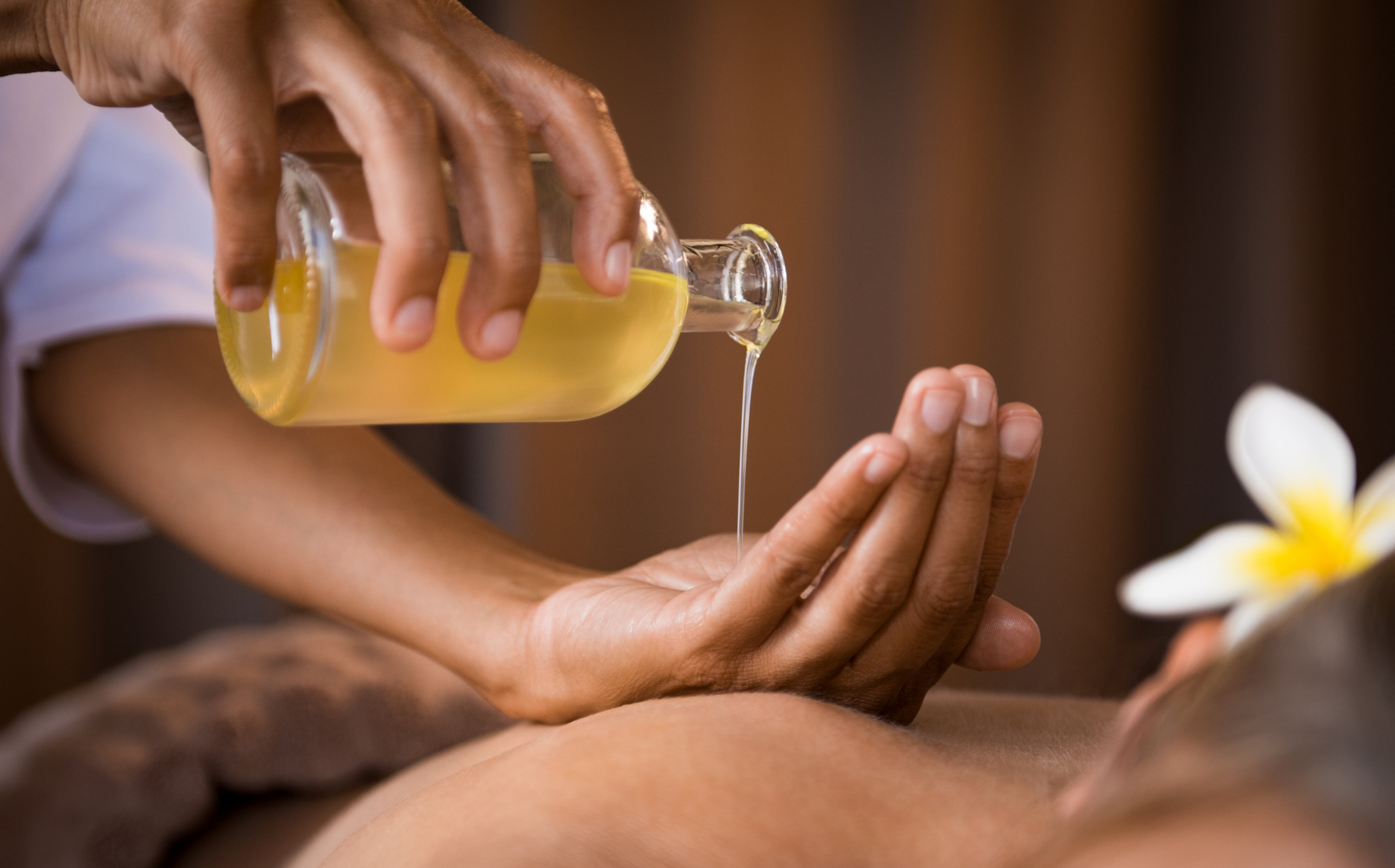Uitgieten olie uit fles tijdens massagebehandeling